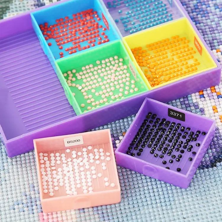 Diamond painting bakjes vierkant in verschillende kleuren met gesorteerde ronde steentjes in diverse kleuren op een canvasachtergrond