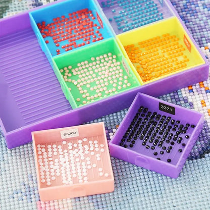 Diamond painting bakjes vierkant in verschillende kleuren met gesorteerde ronde steentjes in diverse kleuren op een canvasachtergrond